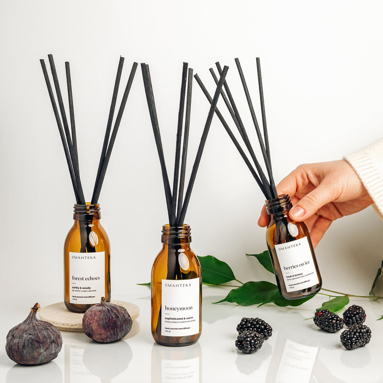 Most Wanted Set de la Omahteka - trio de parfumuri de cameră cu bețișoare din ratan negru în sticle maro cu protecție UV: Berries on Ice, Honeymoon și Forest Echoes.