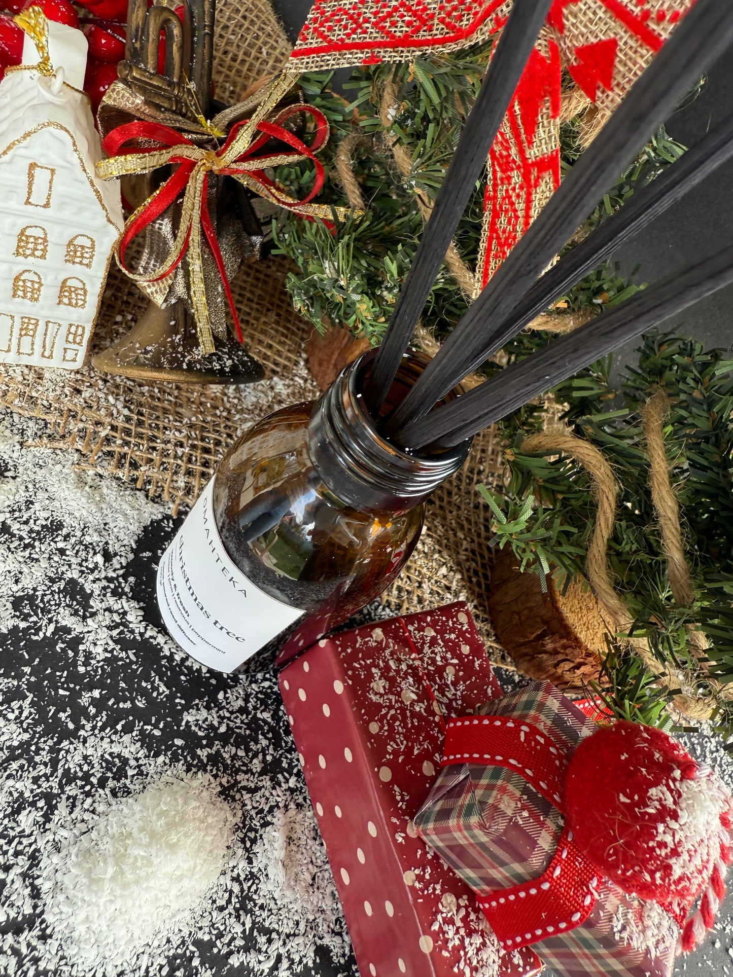 Difuzorul de cameră cu betișoare negre, prezentat într-un decor elegant de Crăciun cu brad și ornamente.