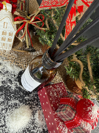 Difuzorul de cameră cu betișoare negre, prezentat într-un decor elegant de Crăciun cu brad și ornamente.