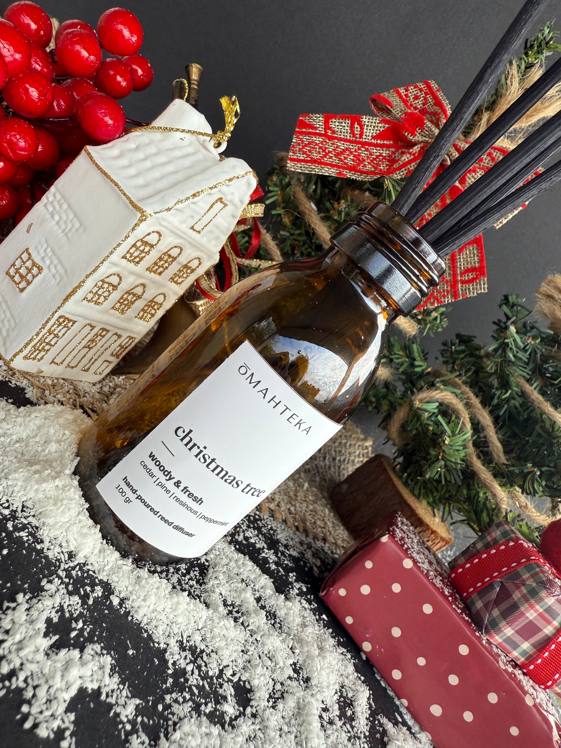 Produs Omahteka cu aromă rășinoasă și verde, fotografiat lângă un brad împodobit și cadouri de Crăciun.