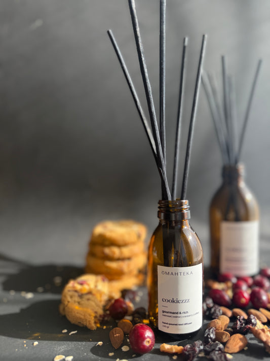 Parfumul de cameră Cookiezzz înconjurat de biscuiți, nuci și elemente dulci specifice sezonului rece.