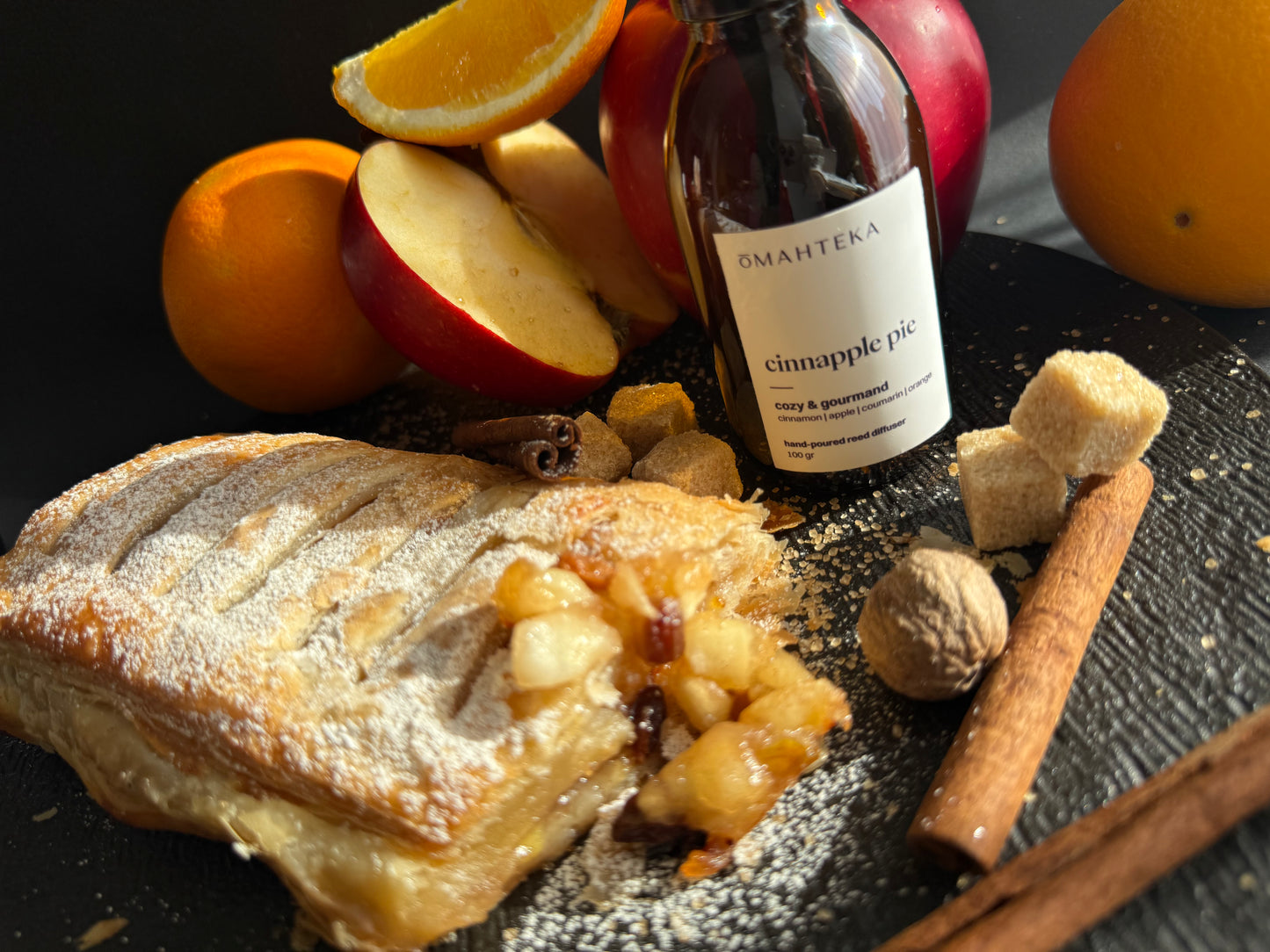 Parfumul Omahteka cu aromă gurmandă de plăcintă cu mere, alături de portocale și bețișoare negre de ratan.