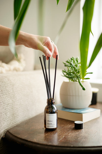 Detaliu difuzor Tall Pines de la Omahteka - betișoarele din ratan absorb și eliberează treptat aroma verde de pin, brad balsamic și cedru, pentru o prospețime constantă în cameră.