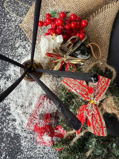 Parfum de cameră în sticlă cu protecție UV, plasat într-un decor festiv cu ornamente și ramuri de brad.