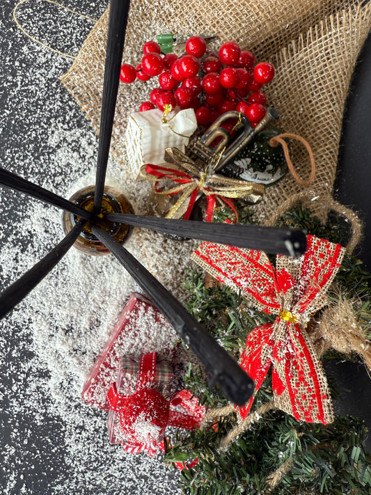 Parfum de cameră în sticlă cu protecție UV, plasat într-un decor festiv cu ornamente și ramuri de brad.