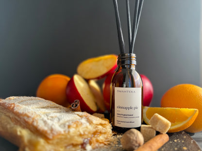 Difuzor Cinnapple Pie într-un setup rustic cu zahăr brun, felii de măr și condimente calde.