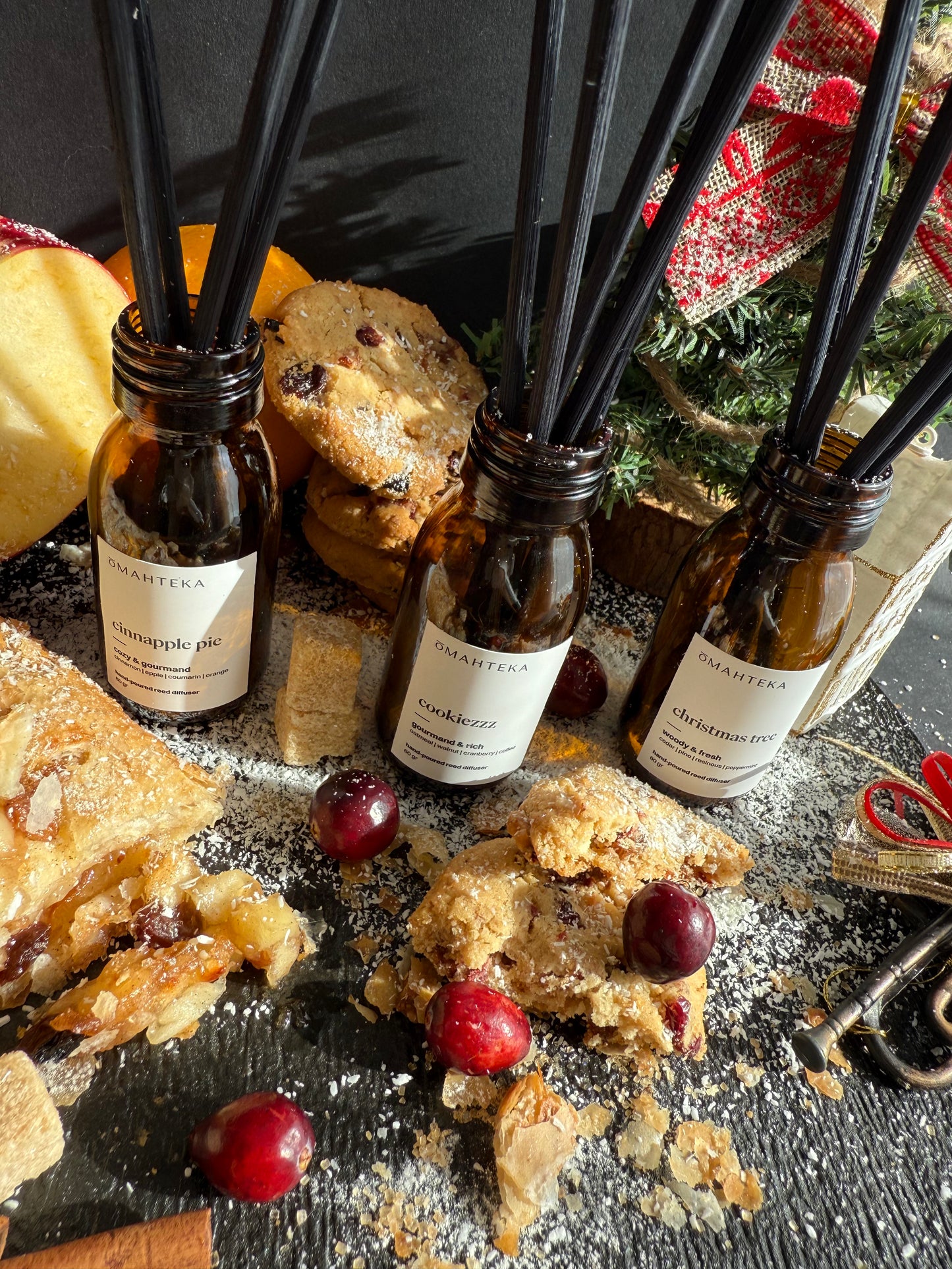 Set de parfumuri de cameră Omahteka plasat într-un decor de Crăciun cu cadouri și ornamente.