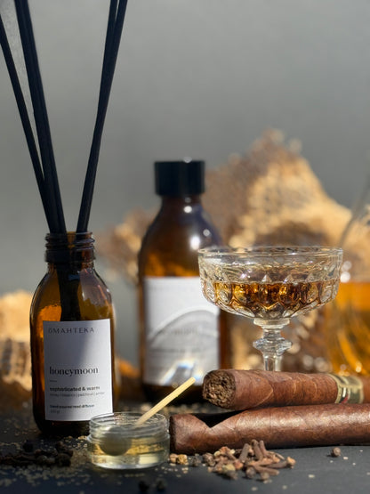 Aromă de cameră Omahteka Honeymoon, cu miros cald de tutun, miere și lemn, într-o prezentare elegantă cu sticlă maro și bețișoare fine.