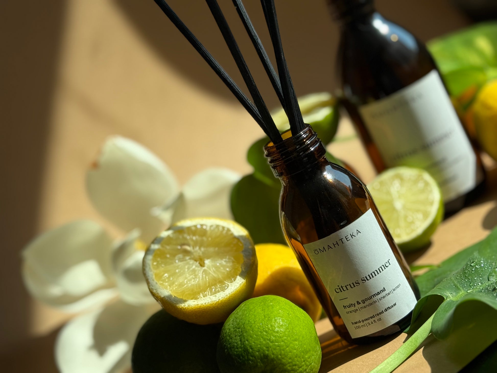 Parfum de cameră cu bețișoare Citrus Summer, plasat într-un decor cu frunze verzi, stropi de apă și felii de citrice – efect fresh garantat.